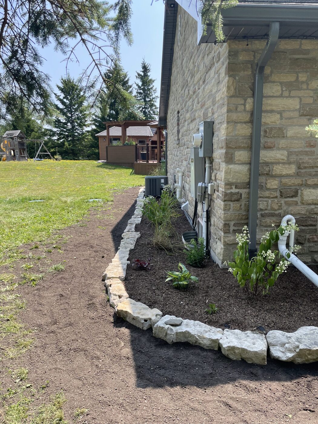 The same side garden after with new stone edging, mulch and plantings