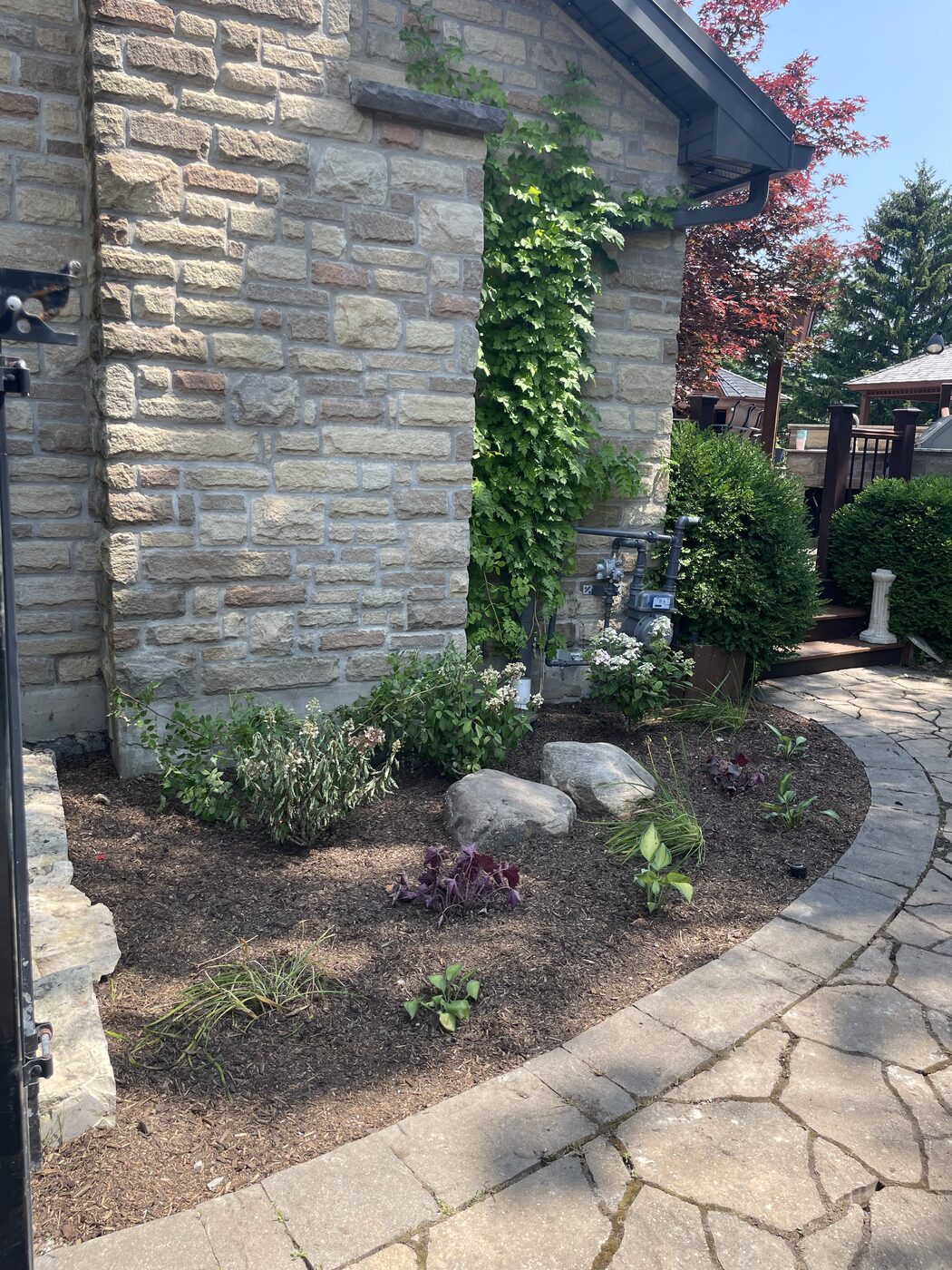 The same corner after cleanup with a fresh garden bed and boulders