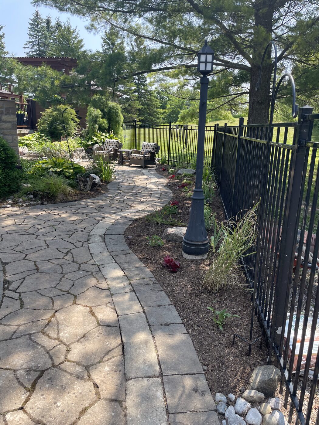 The same walkway after with a manicured garden and clean stone path