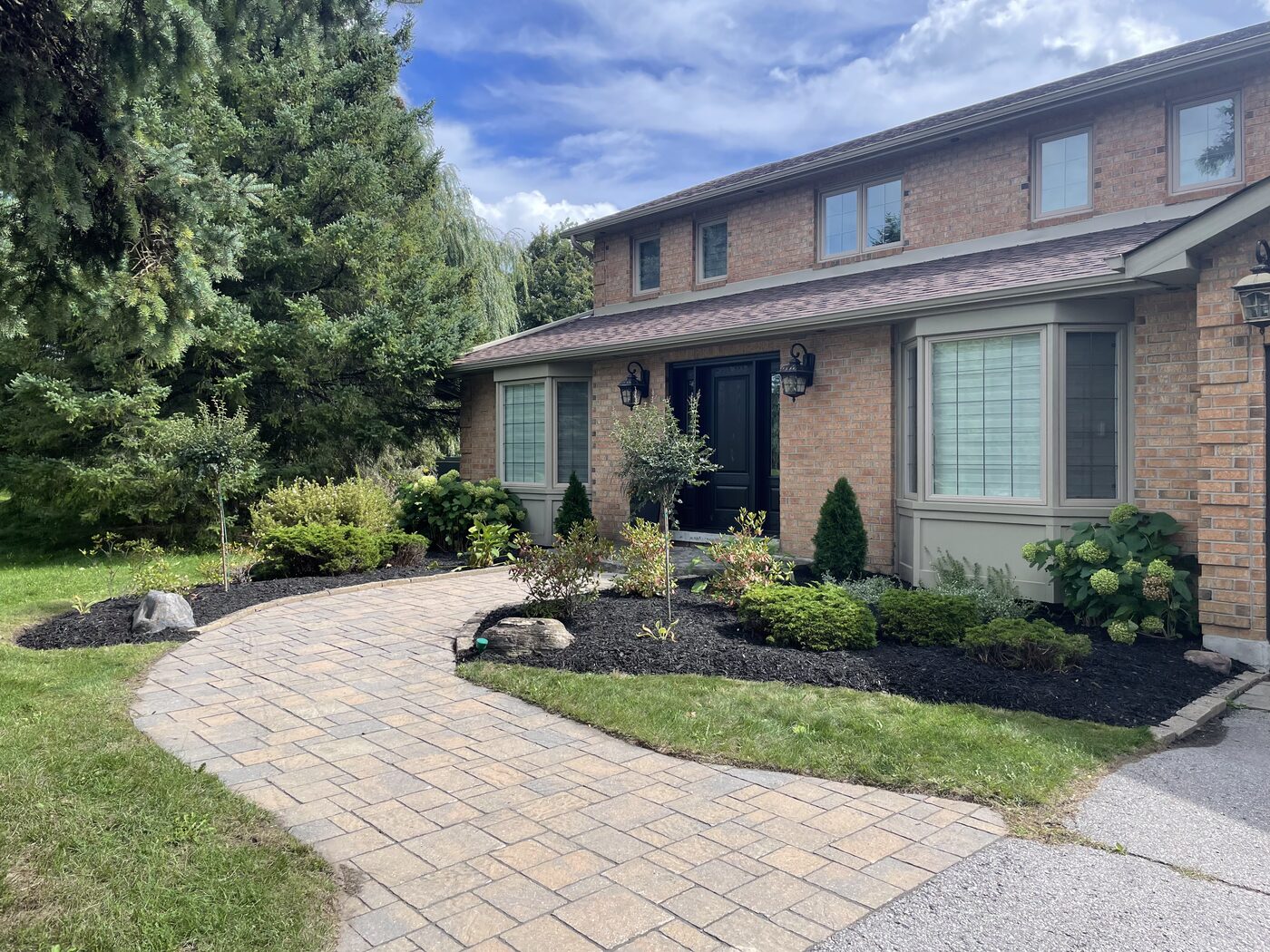Curved paver walkway and mulched beds at a brick home
