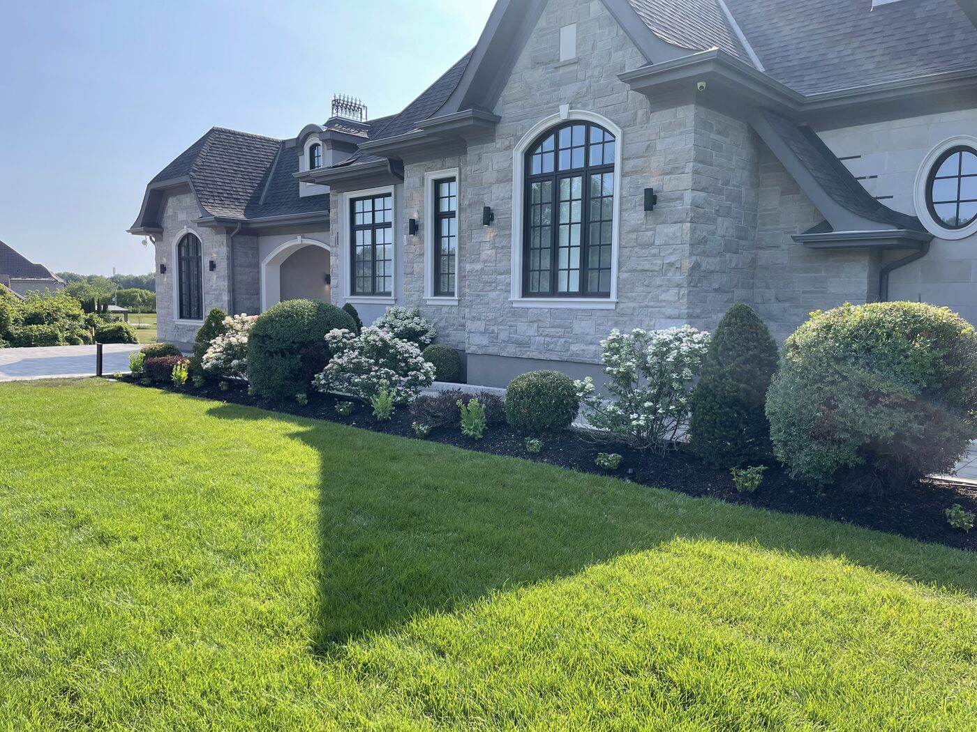 Manicured gardens and lawn at a white stone home