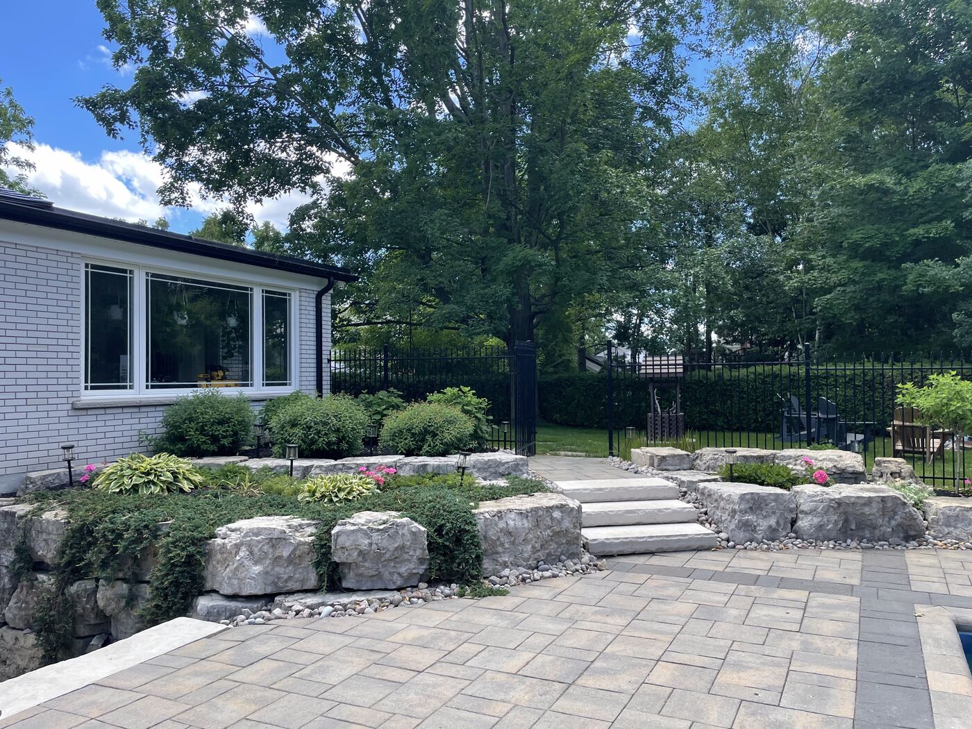 Paver patio with stone steps and garden beds